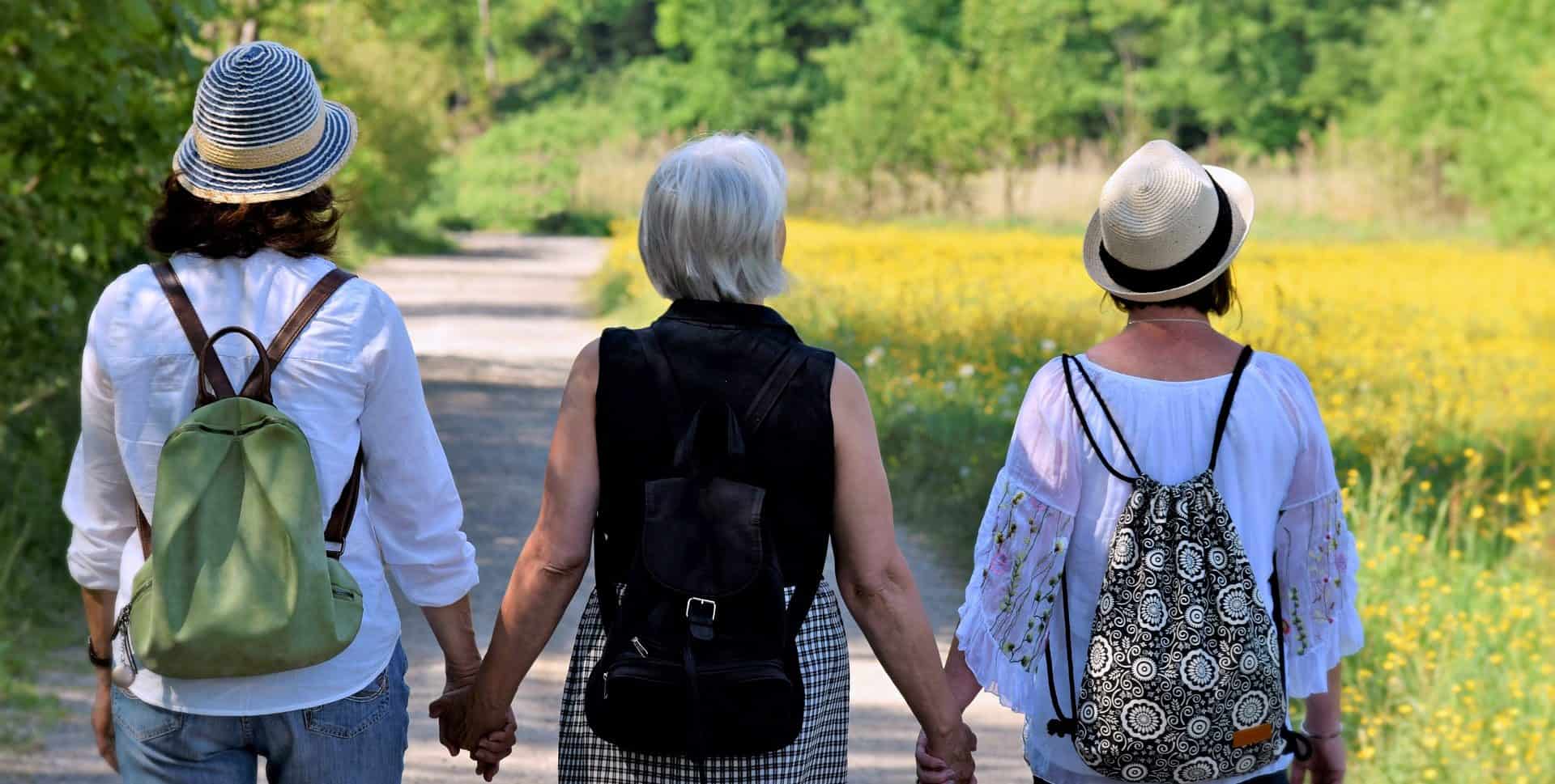 three women friends walking hand in hand down road
